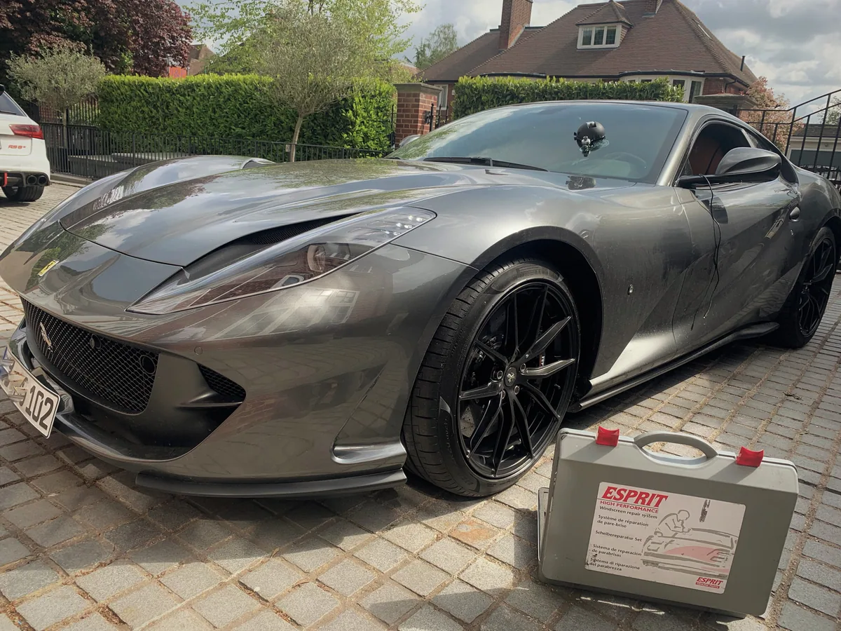 Resin chip repair underway on a grey Aston Martin windscreen.