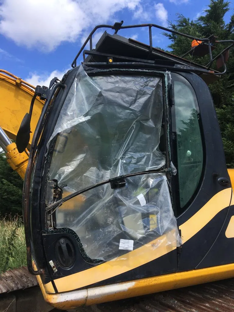 JCB JS130 excavator with broken cab door glass before replacement.