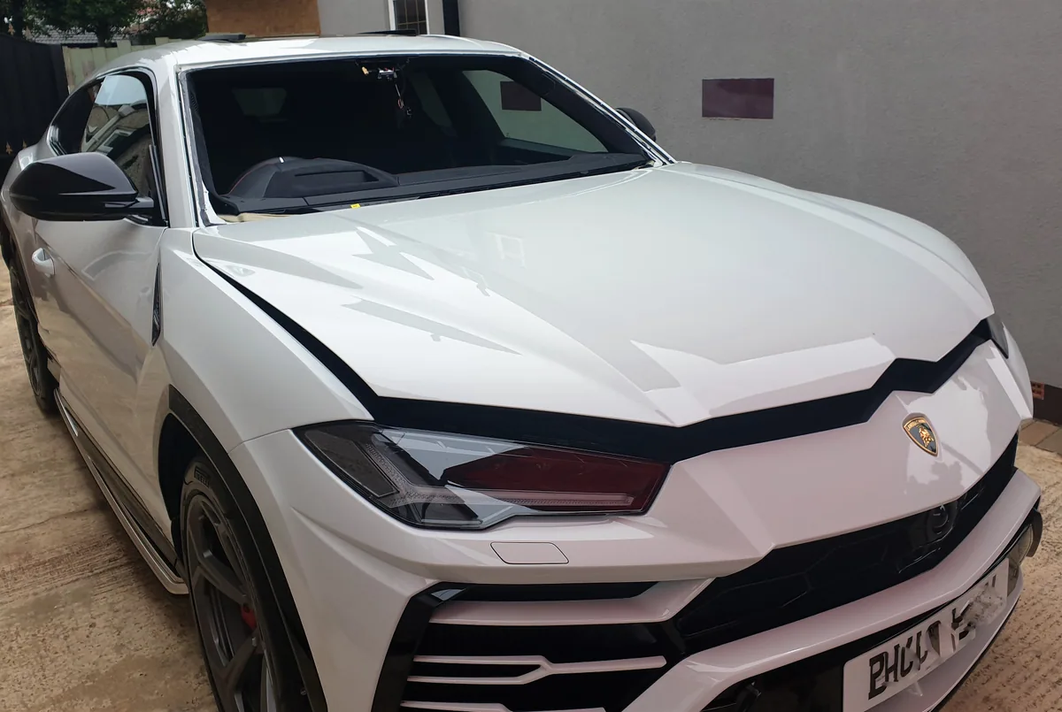 White Lamborghini Urus in the workshop with the windscreen lifted out.