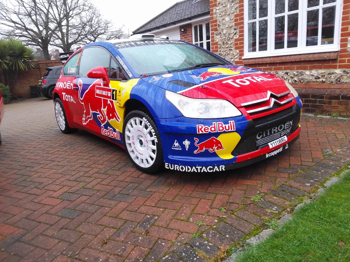 Blue and yellow rally car with replacement windscreen.
