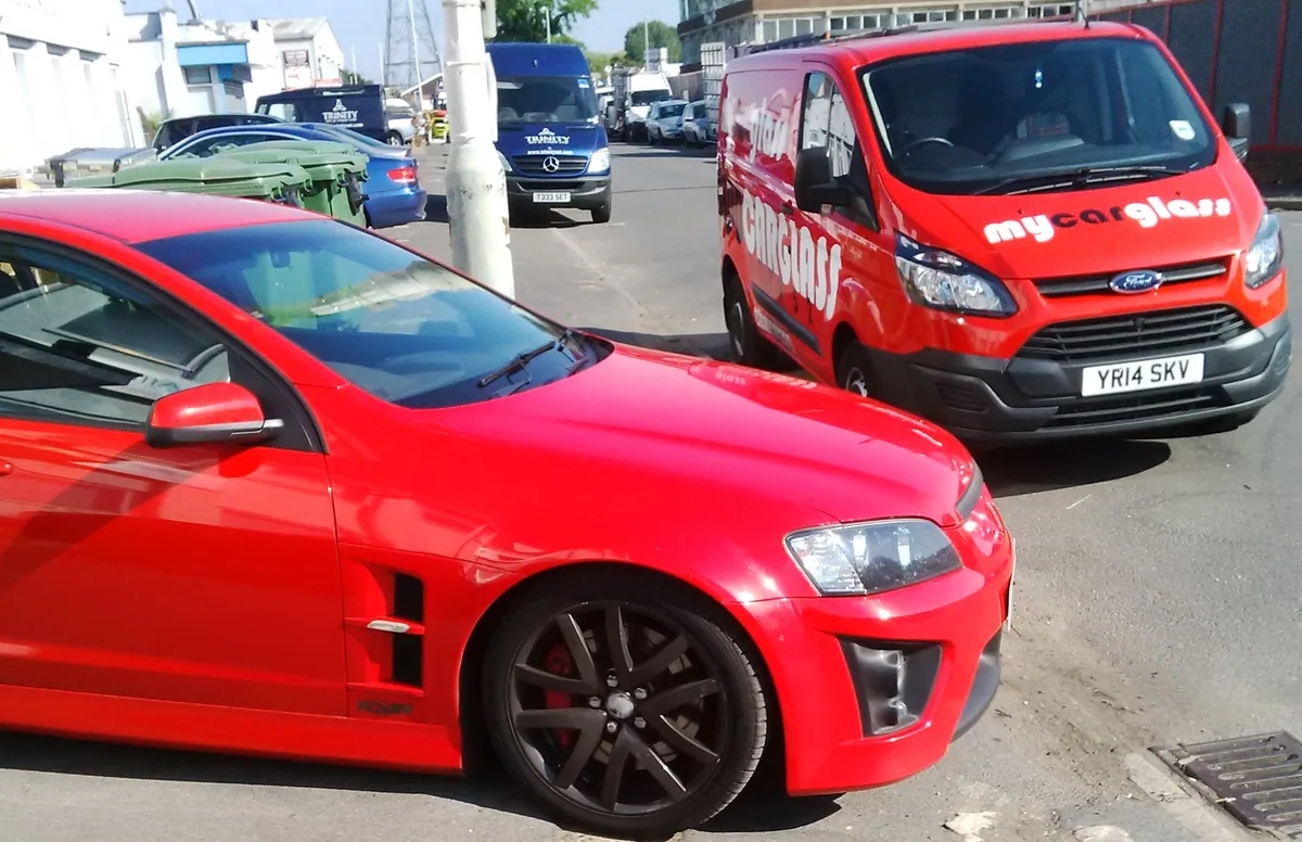 Red sports car with the MyCarGlass van during a mobile job on the street.