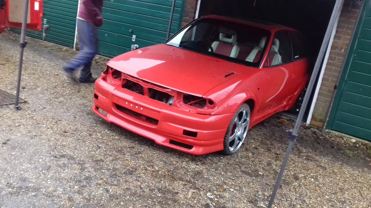 Red sports car during windscreen replacement in the workshop.