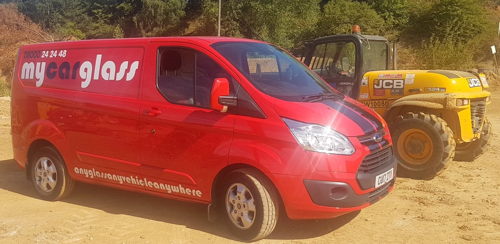 The red MyCarGlass van parked next to a JCB wheel loader on a working site.